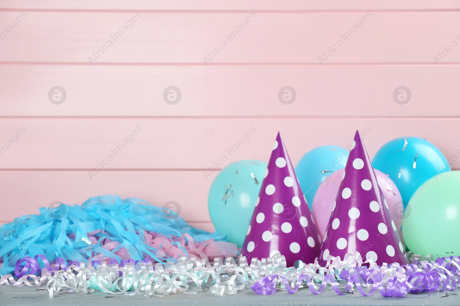 Photo of Colorful serpentine streamers and other party accessories on grey wooden table. Space for text