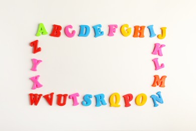 Photo of Frame of colorful magnetic letters on white background, flat lay with space for text. Alphabetic order