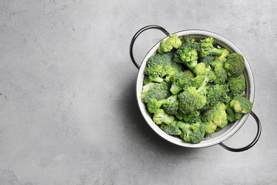 Photo of Colander with fresh green broccoli on grey background, top view