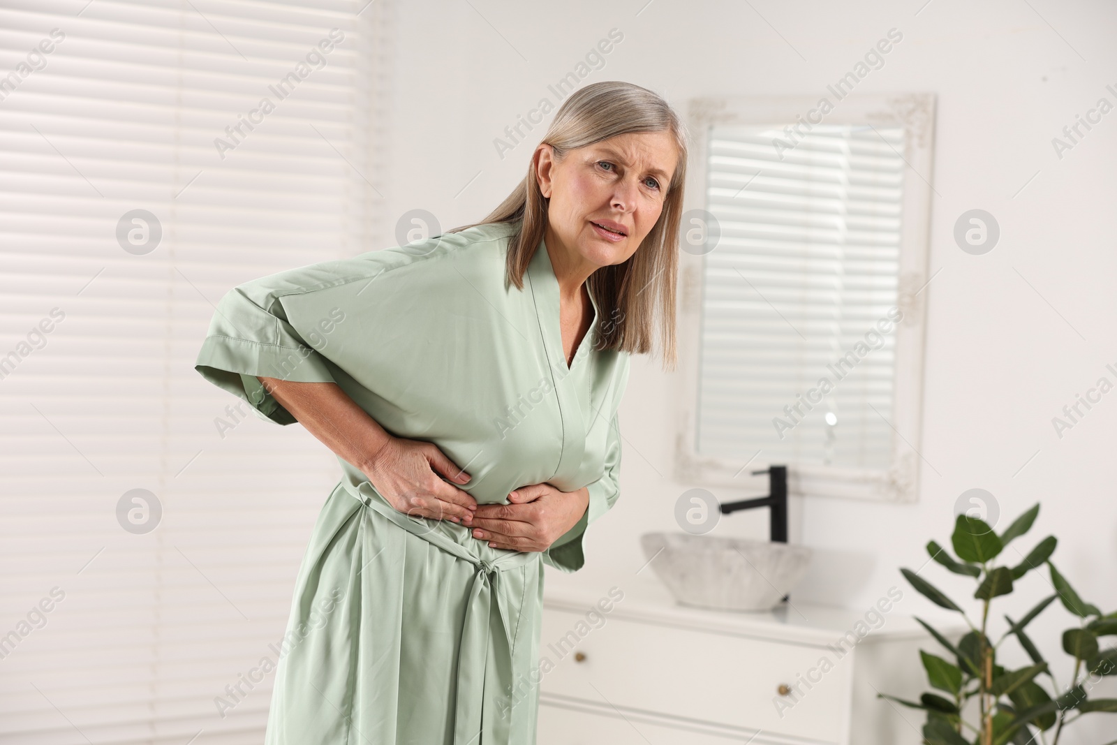 Photo of Menopause. Woman suffering from digestive problems in bathroom, space for text