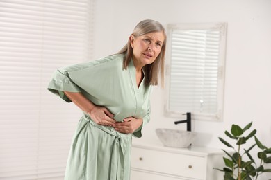 Photo of Menopause. Woman suffering from digestive problems in bathroom, space for text