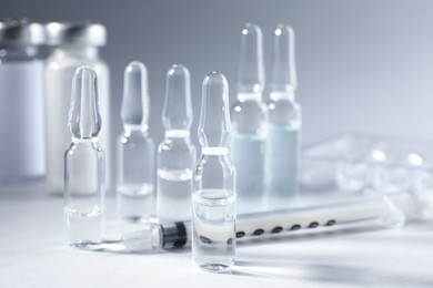 Pharmaceutical ampoules and syringe on light grey background