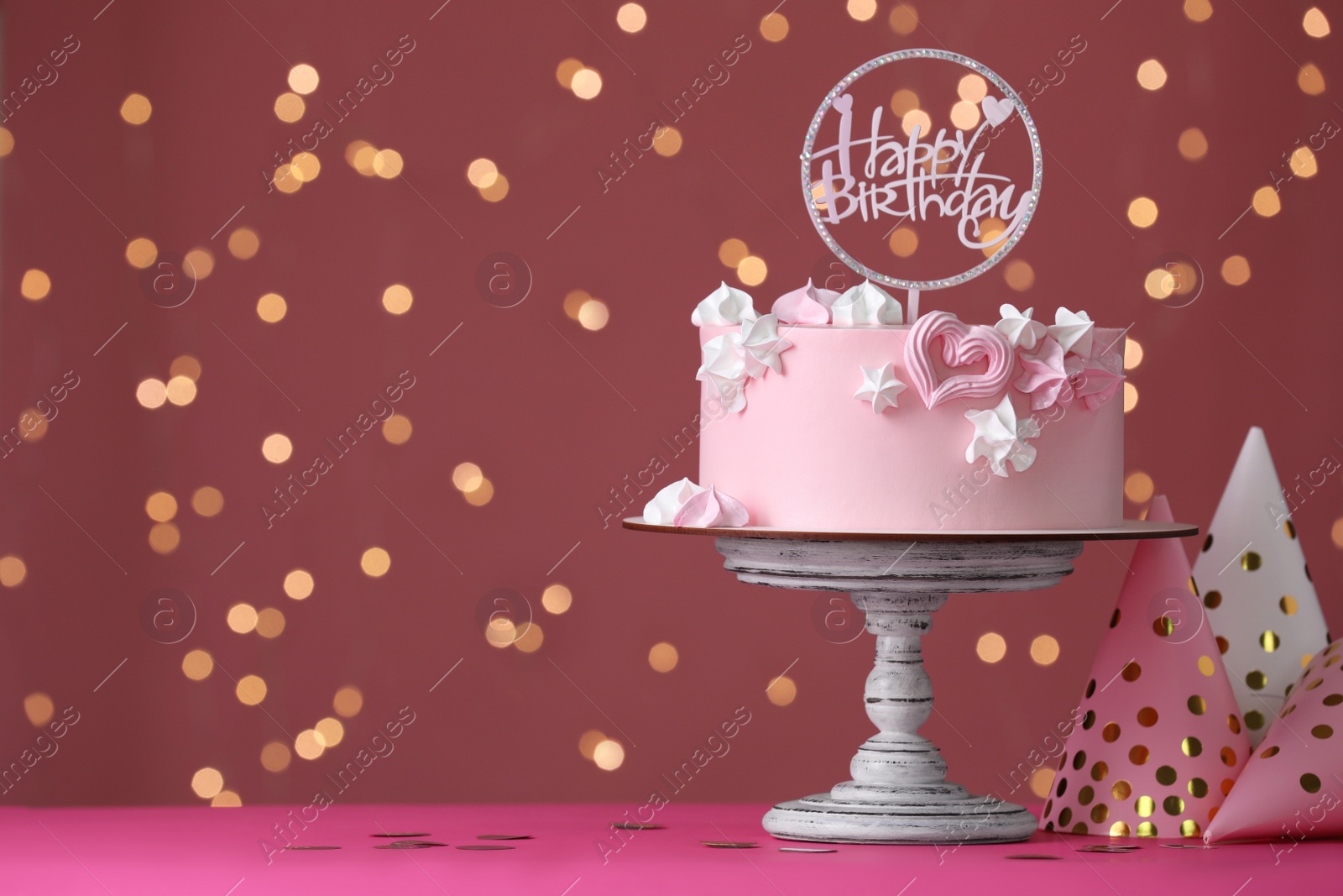 Photo of Beautifully decorated birthday cake on pink table against blurred festive lights, space for text