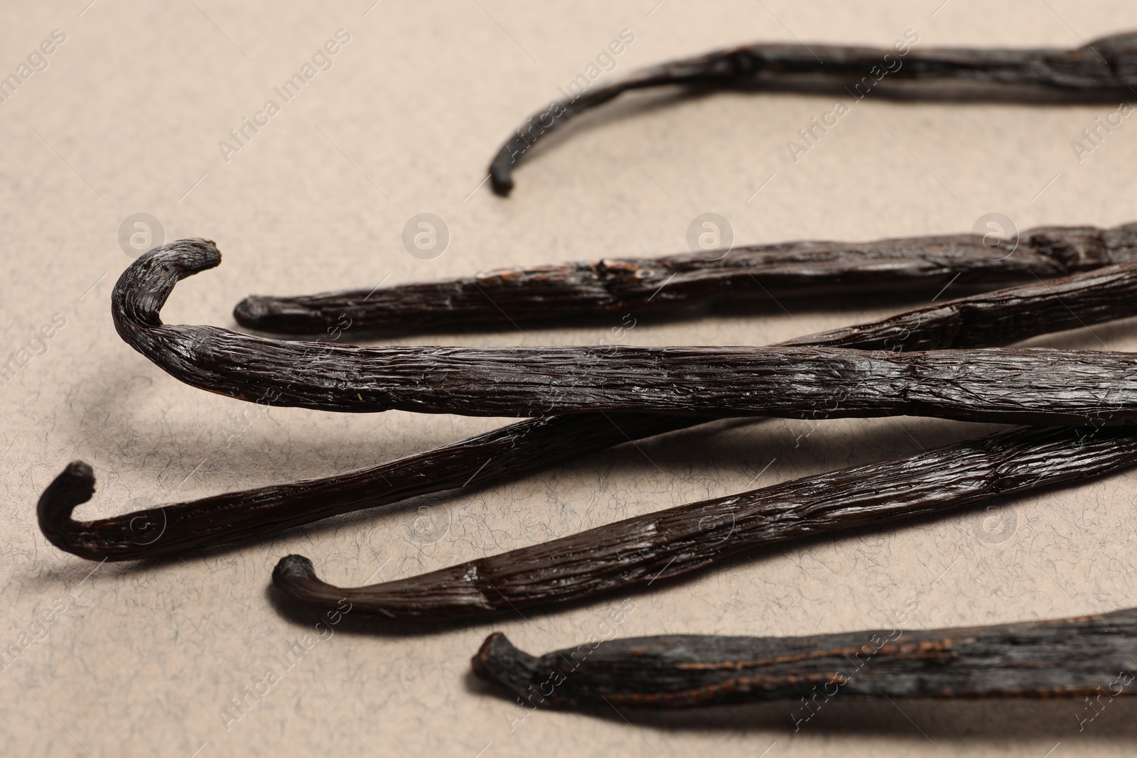 Photo of Many vanilla pods on beige background, closeup