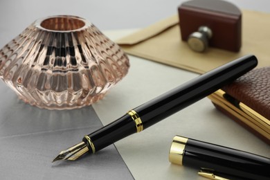 Photo of Stylish fountain pen, inkwell and paper on grey textured table, closeup