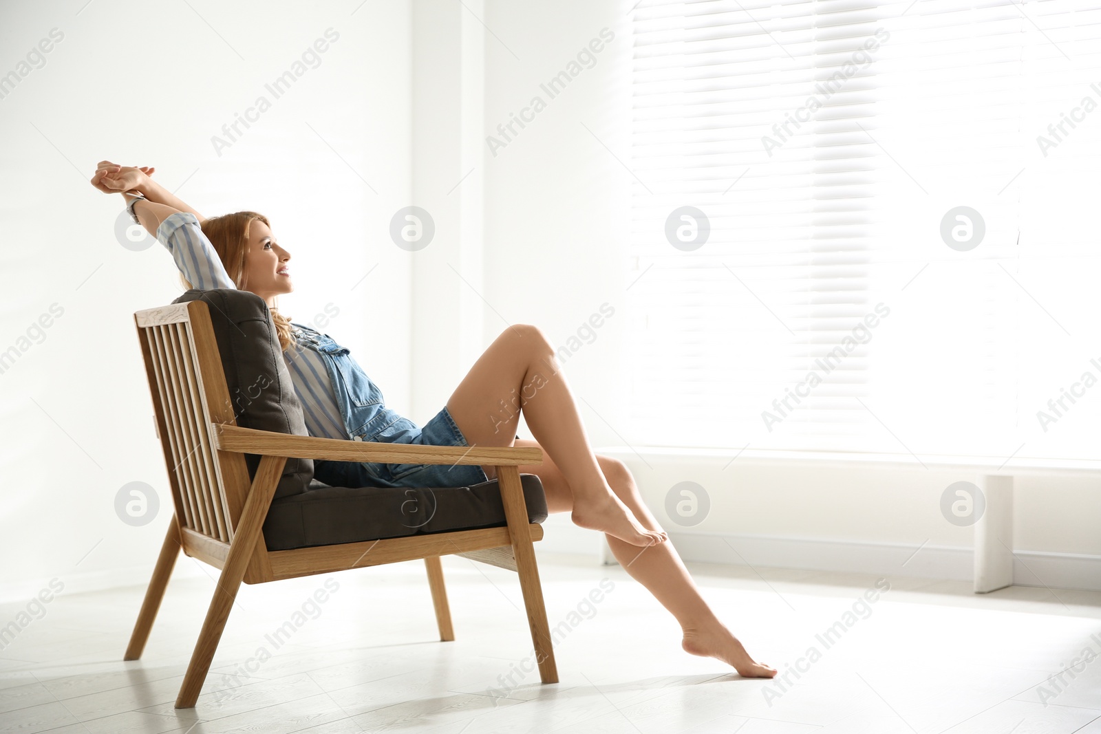 Photo of Young woman relaxing in armchair near window at home. Space for text