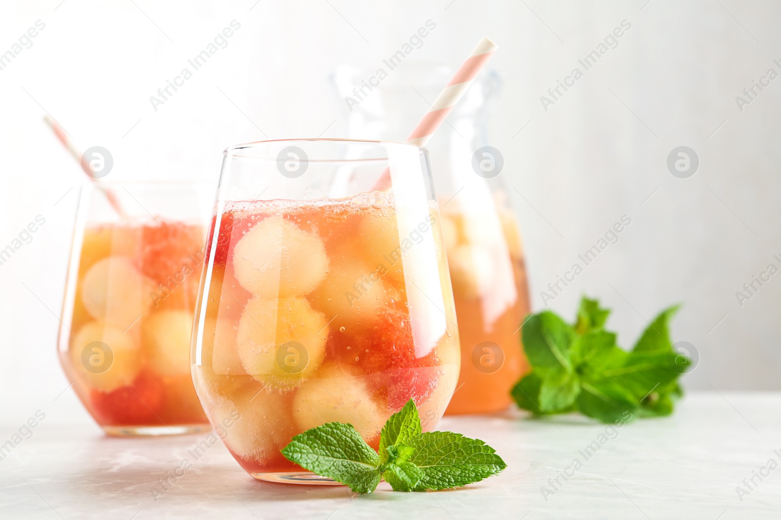 Photo of Glasses of melon and watermelon ball cocktail with mint on white table