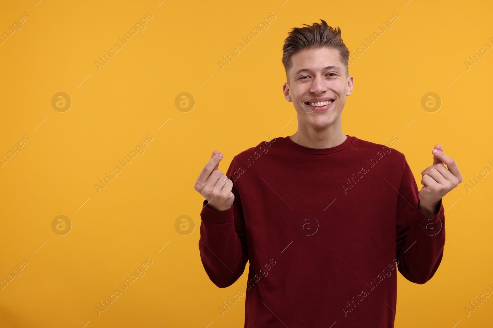 Photo of Happy man showing money gesture on yellow background. Space for text