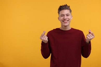 Happy man showing money gesture on yellow background. Space for text