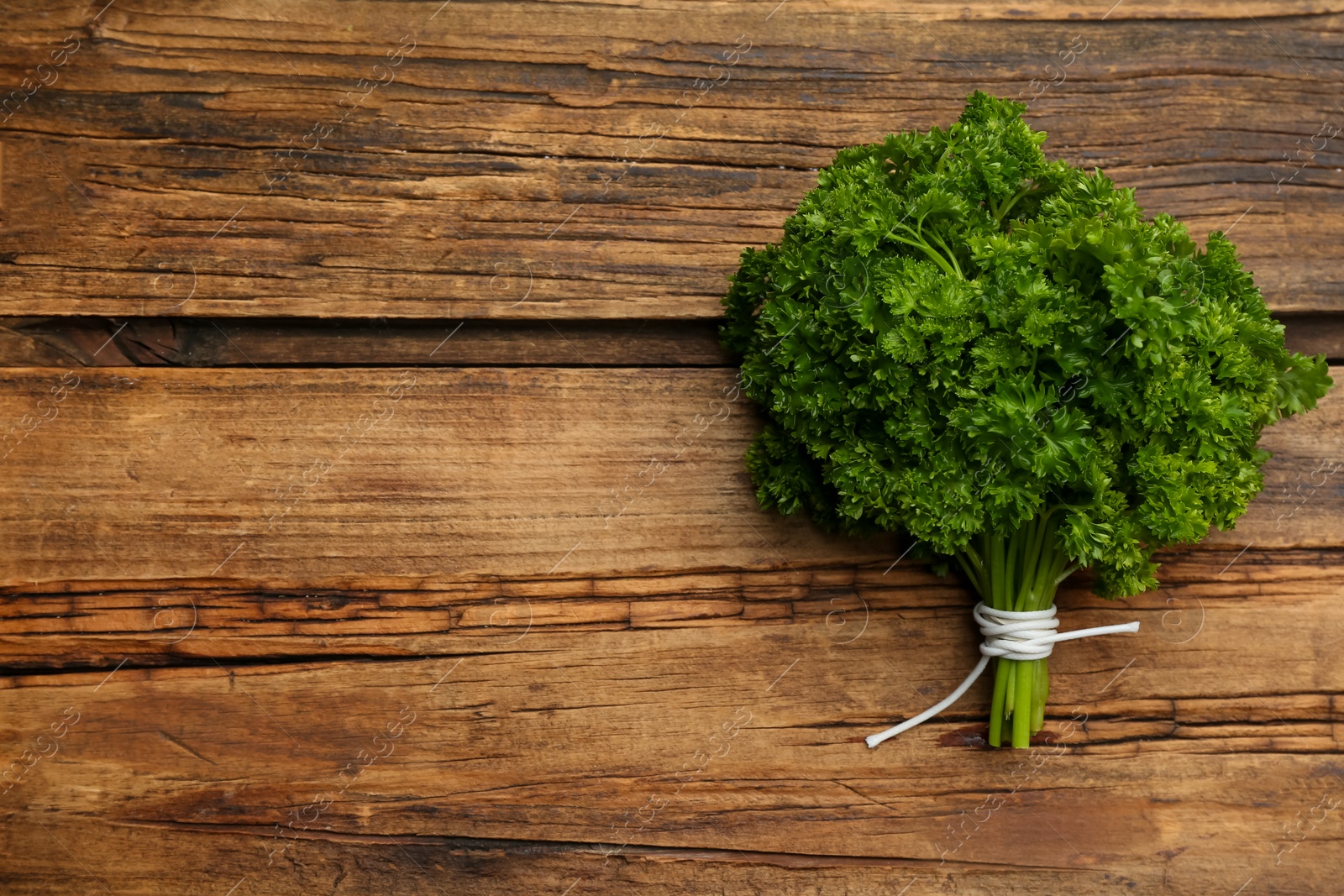 Photo of Bunch of fresh curly parsley on wooden table, top view. Space for text