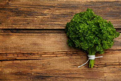 Bunch of fresh curly parsley on wooden table, top view. Space for text