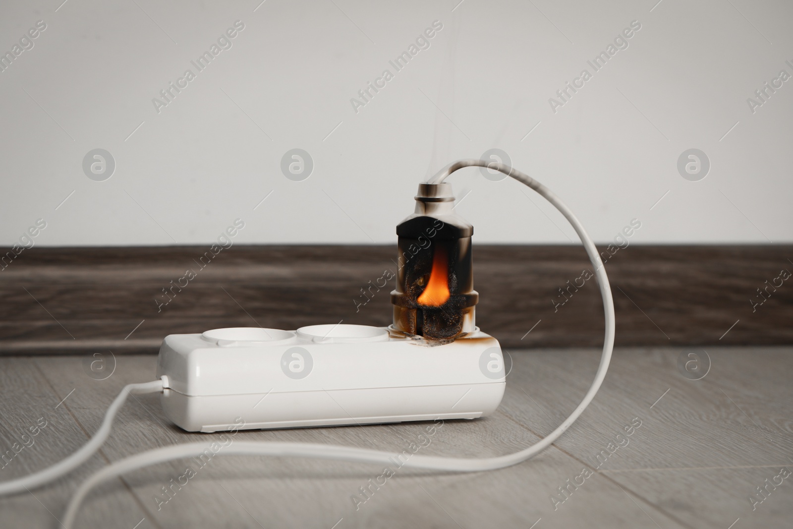 Photo of Inflamed plug in power strip indoors. Electrical short circuit