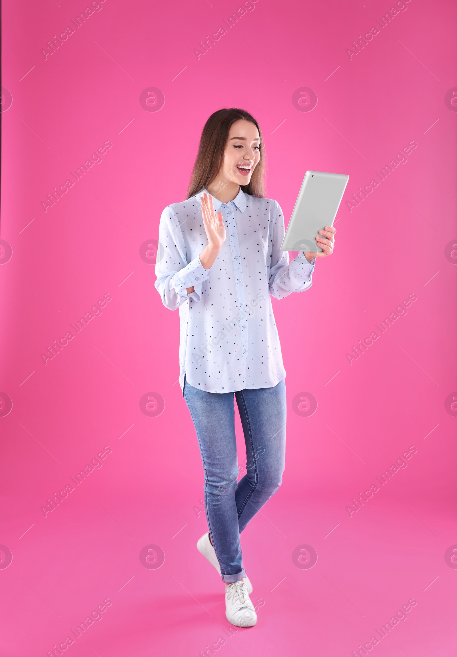 Photo of Woman using tablet for video chat on color background