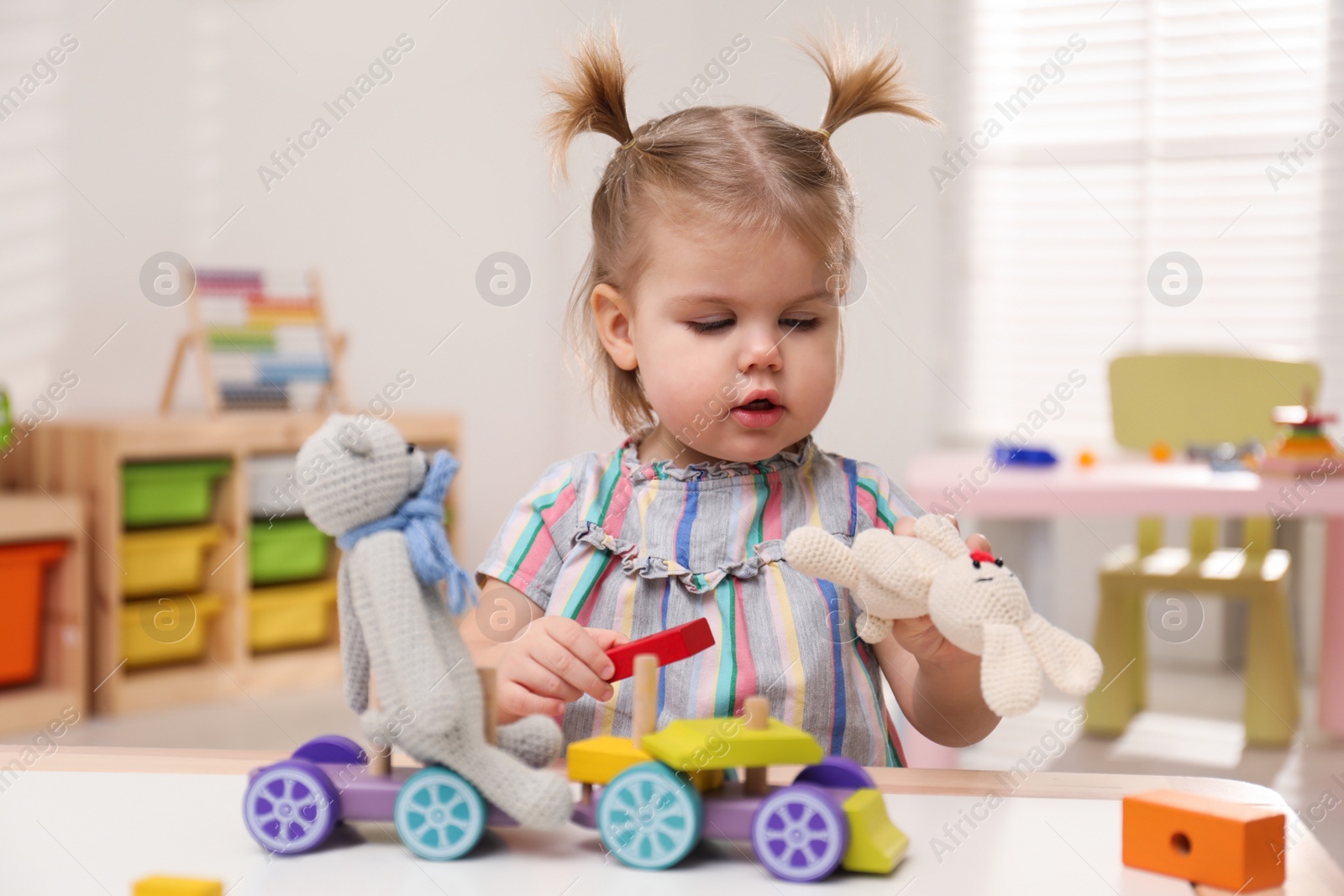 Photo of Little girl playing with toys at table