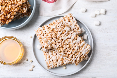 Photo of Delicious rice crispy treats on white wooden table, flat lay