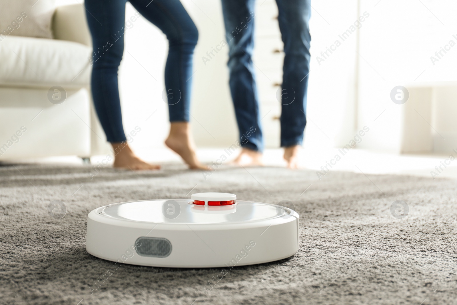 Photo of Couple using robotic vacuum cleaner at home