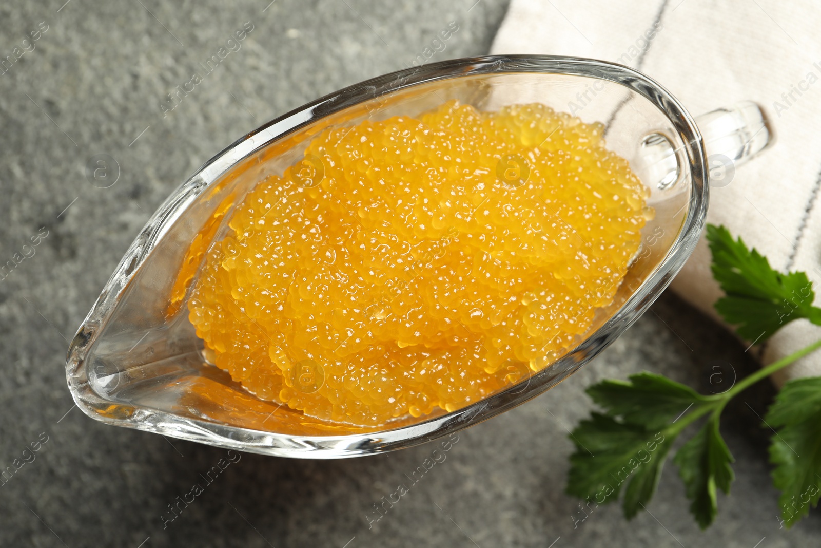 Photo of Fresh pike caviar in gravy boat and parsley on grey table, top view