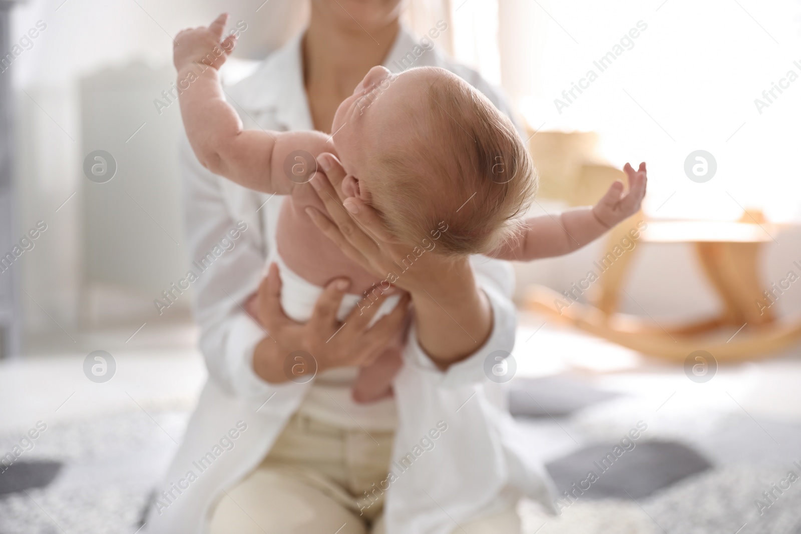 Photo of Young mother with her little baby sitting on floor at home, closeup