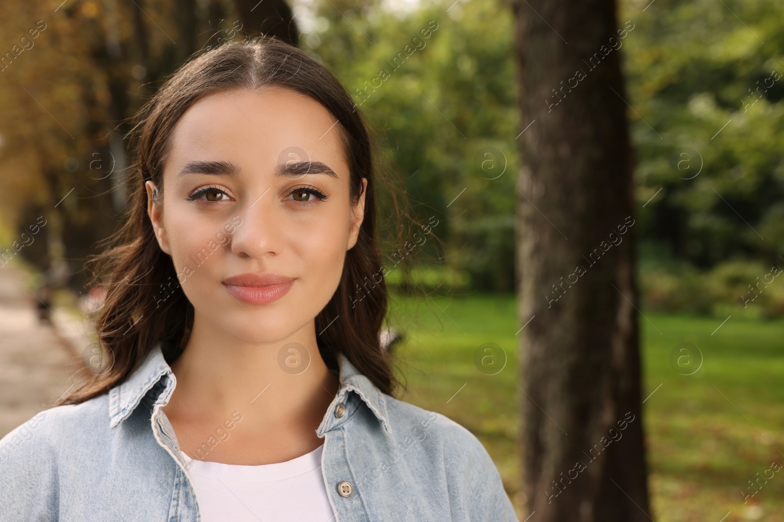 Photo of Portrait of beautiful young woman in park. Space for text