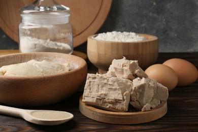 Photo of Different types of yeast, eggs, flour and dough on wooden table