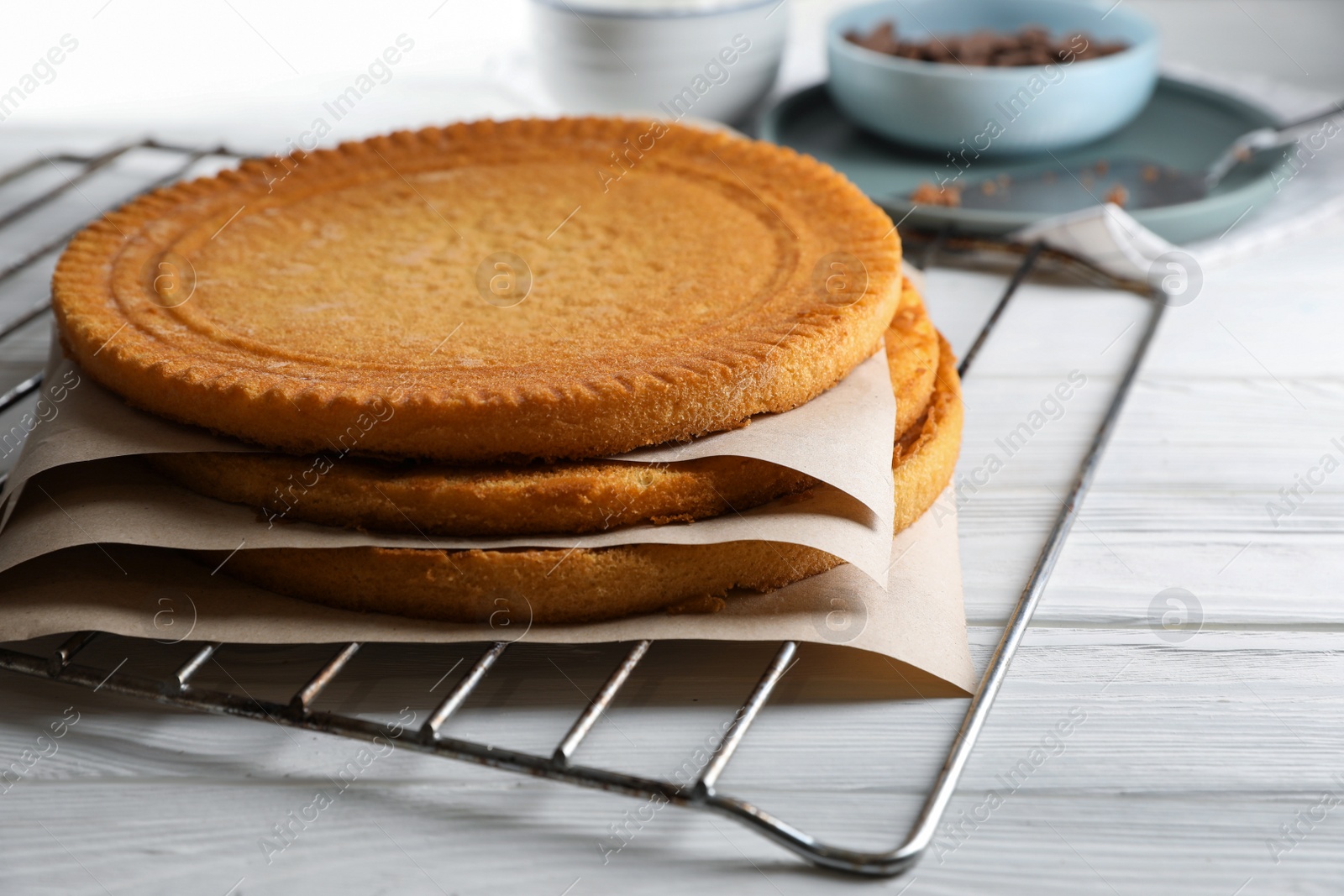 Photo of Delicious homemade sponge cakes with parchment on white wooden table, closeup