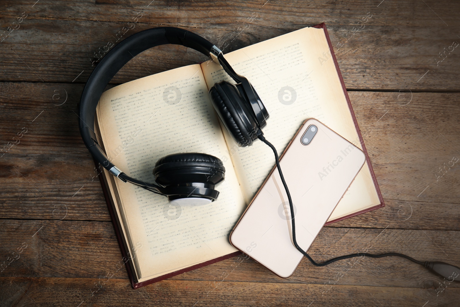 Photo of Book, modern headphones and smartphone on wooden table, flat lay