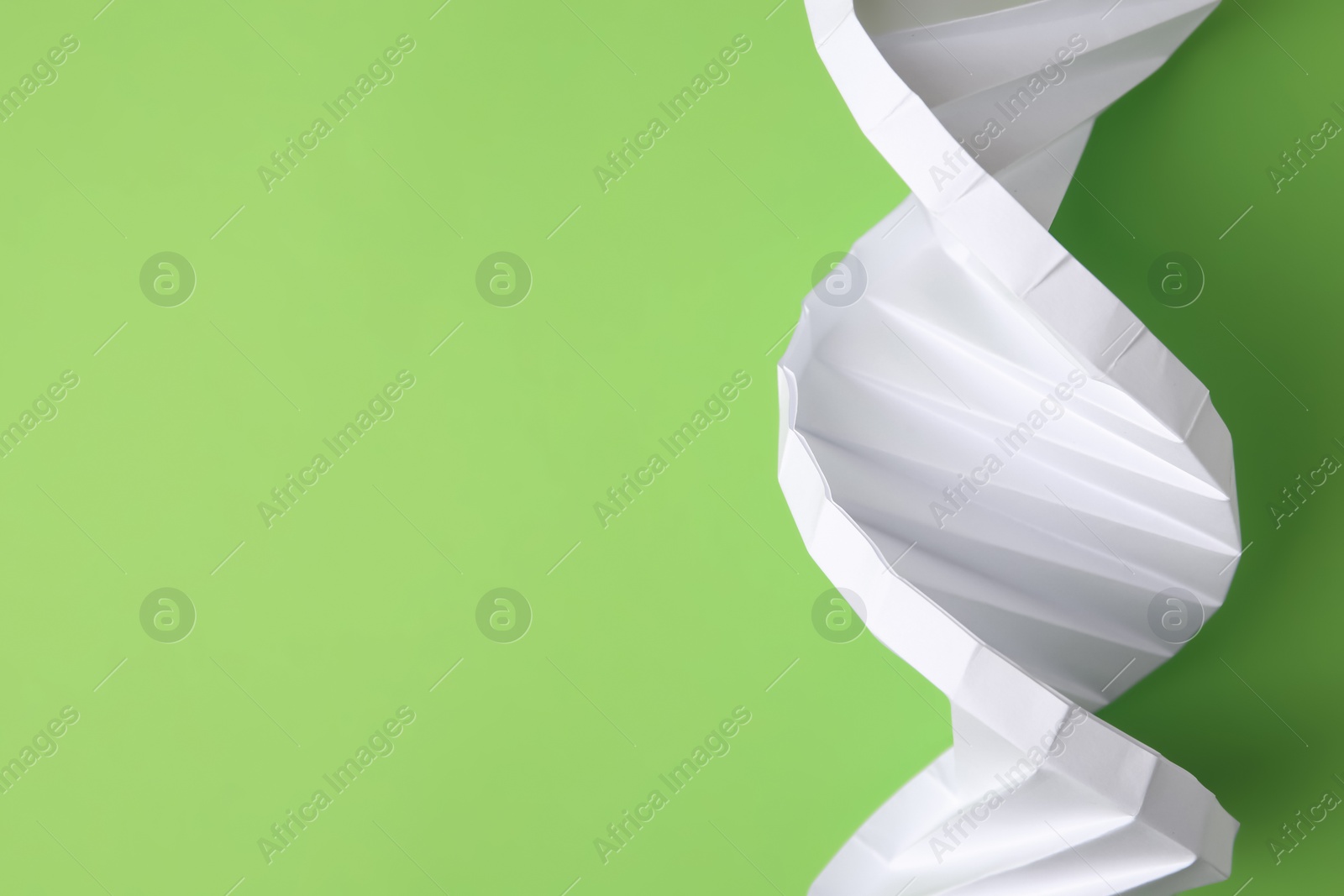 Photo of Paper model of DNA molecular chain on green background, top view. Space for text