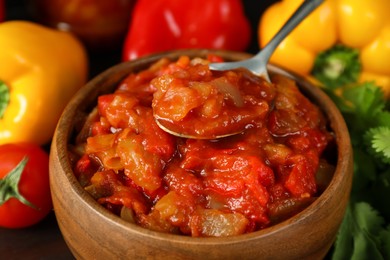 Photo of Tasty lecho in wooden bowl and fresh ingredients, closeup