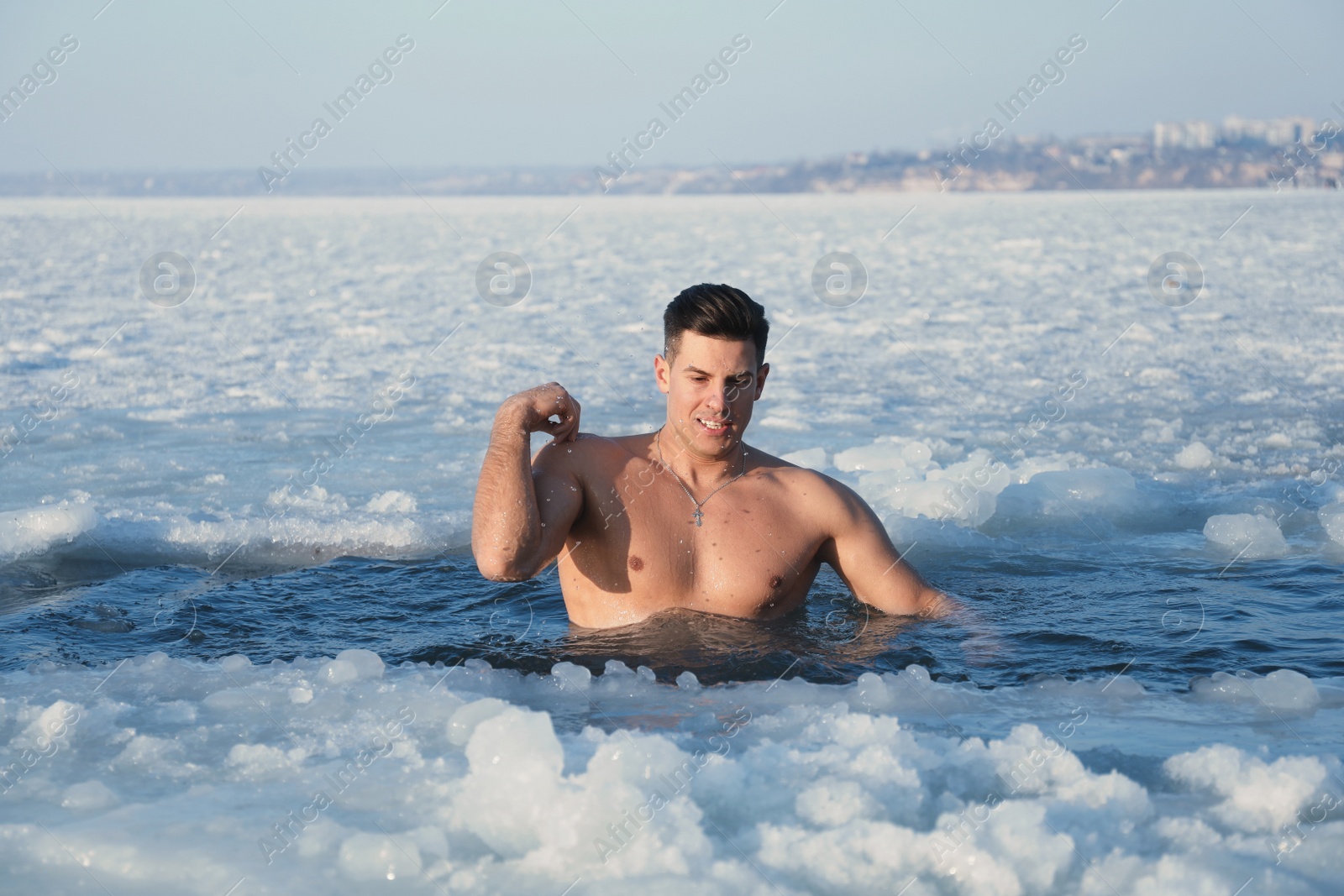 Photo of Man immersing in icy water on winter day. Baptism ritual