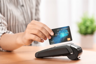 Woman using terminal for credit card payment indoors