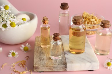 Photo of Aromatherapy. Different essential oils and flowers on pink background