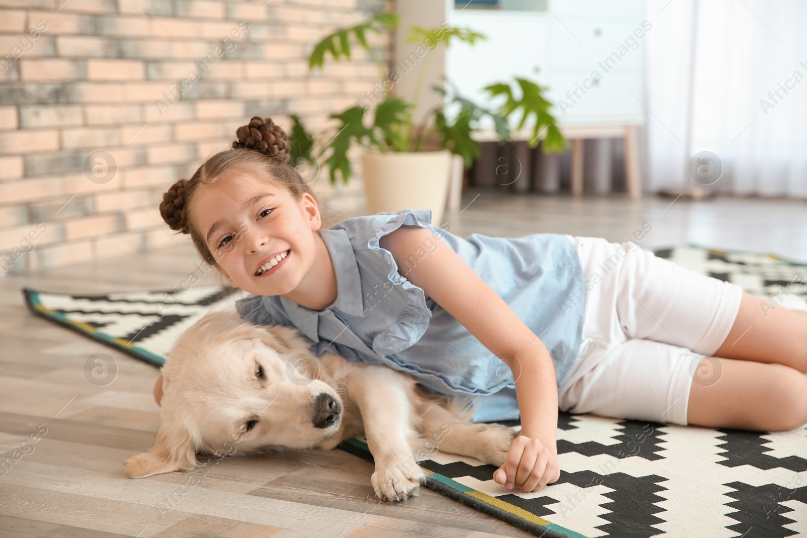 Photo of Cute little child with her pet on floor at home