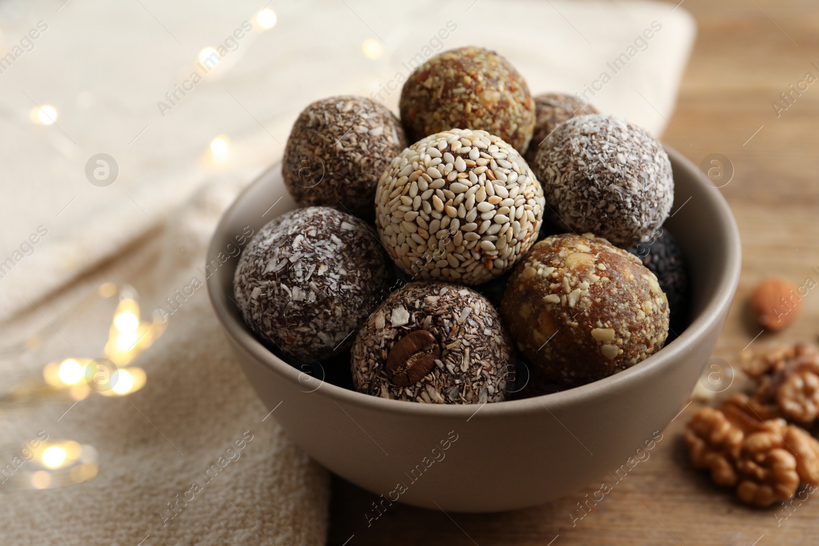 Photo of Different delicious vegan candy balls on wooden table, closeup