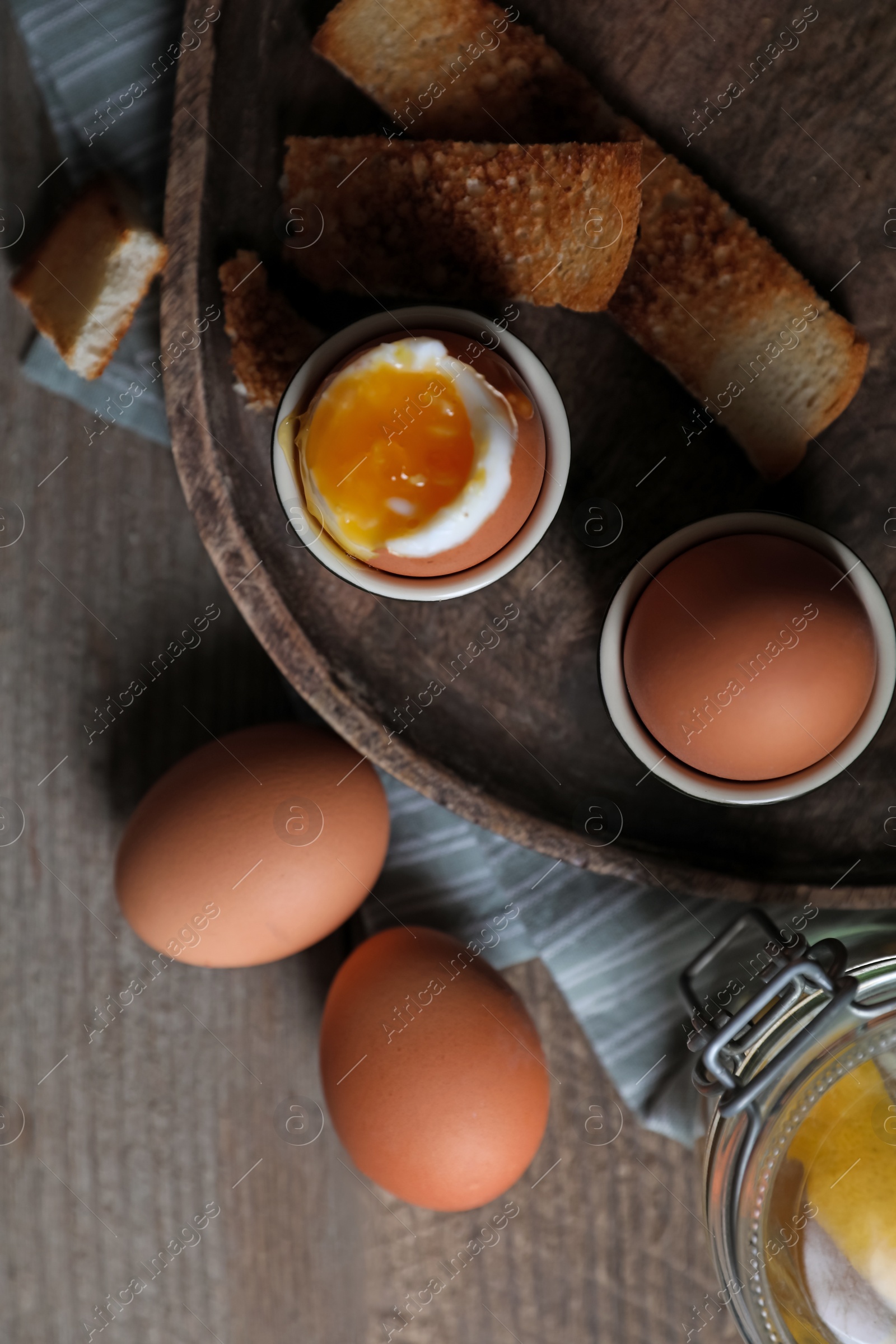 Photo of Tasty boiled eggs in cups on wooden table, flat lay