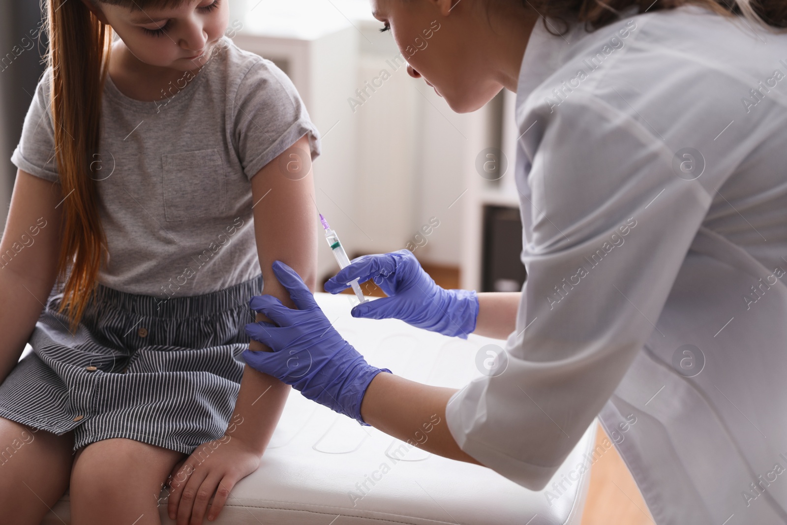 Photo of Little girl receiving chickenpox vaccination in clinic. Varicella virus prevention