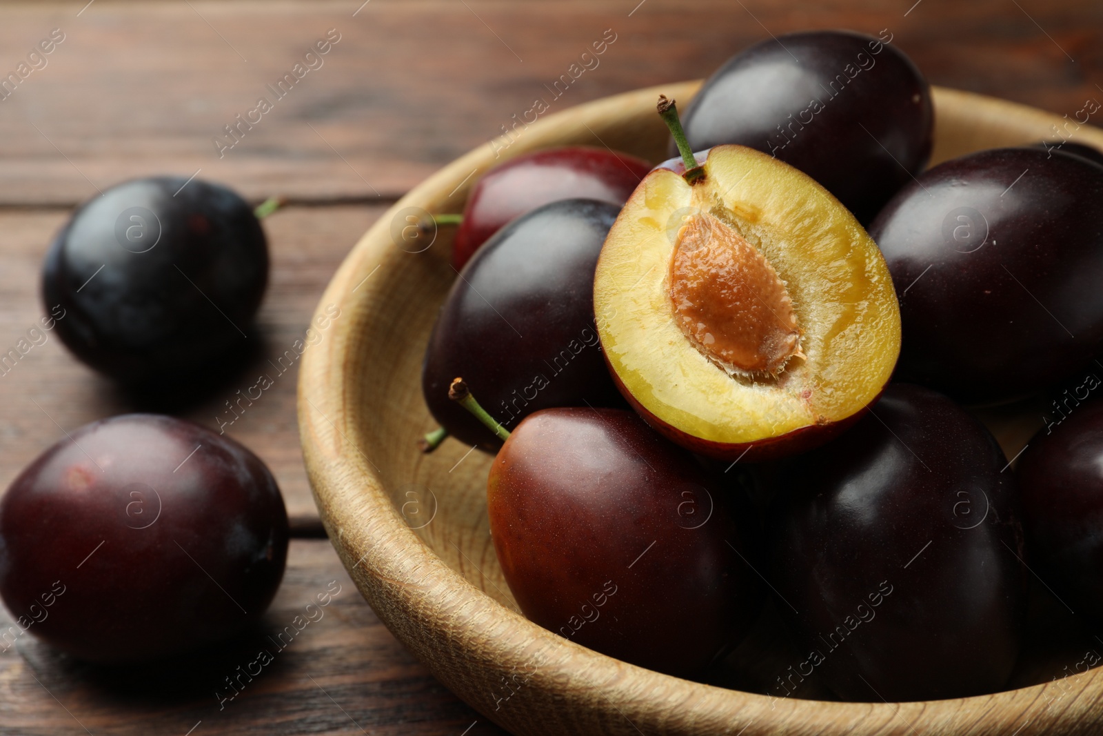 Photo of Tasty ripe plums on wooden table, closeup