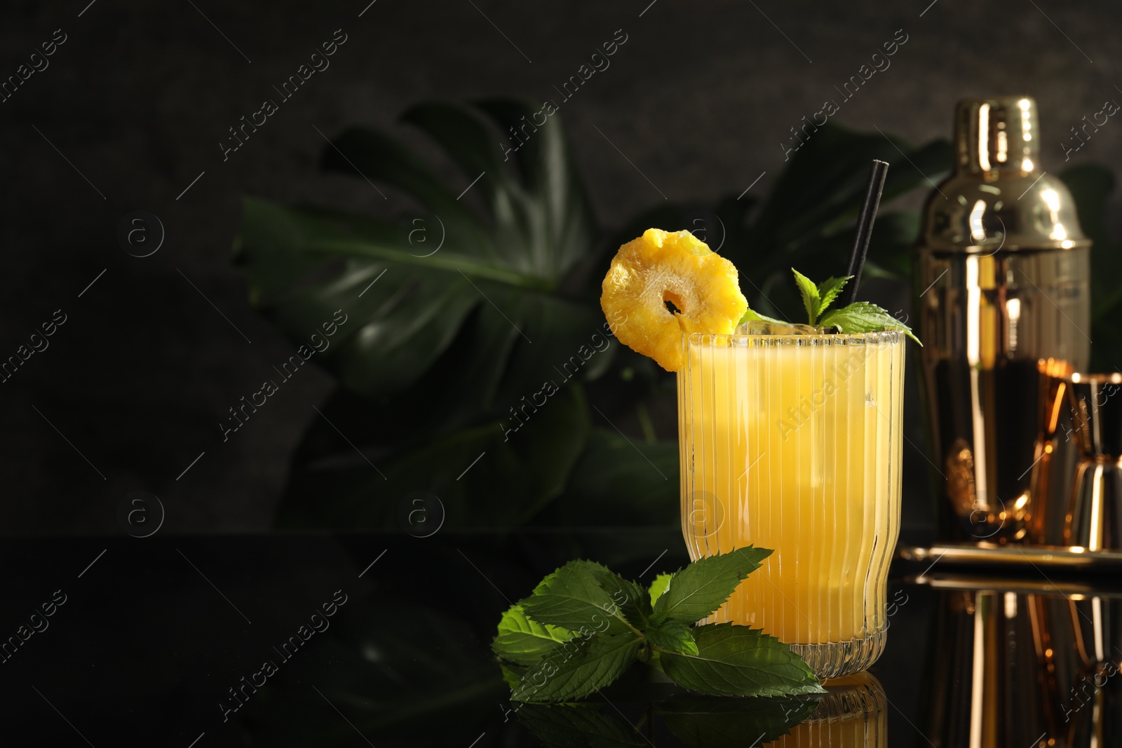 Photo of Tasty pineapple cocktail with mint on black mirror surface. Space for text