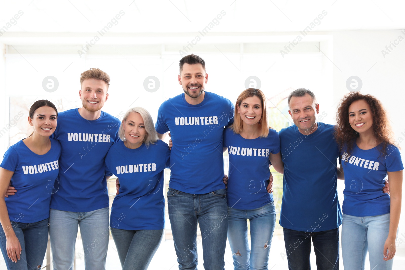 Photo of Team of volunteers in uniform on light background