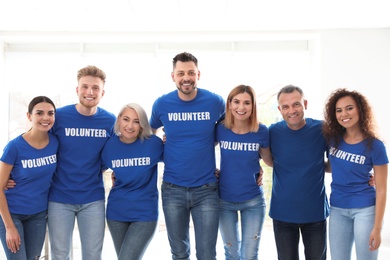 Team of volunteers in uniform on light background