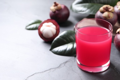 Photo of Delicious fresh mangosteen juice in glass on table, space for text
