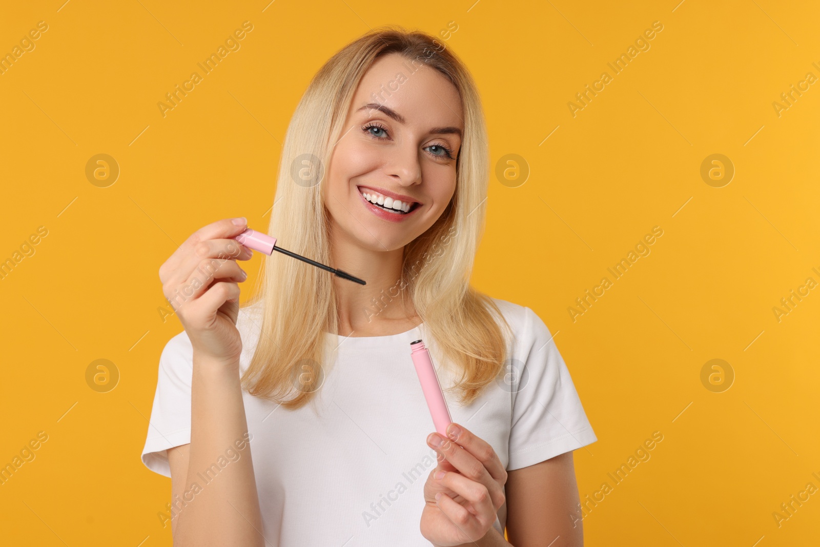 Photo of Beautiful woman with mascara on orange background