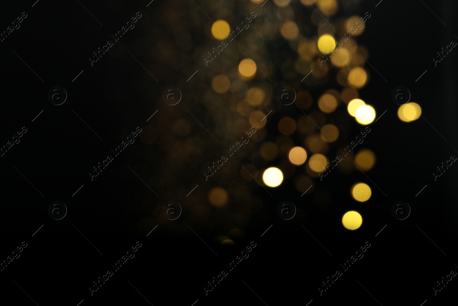 Photo of Blurred view of golden lights on black background. Bokeh effect