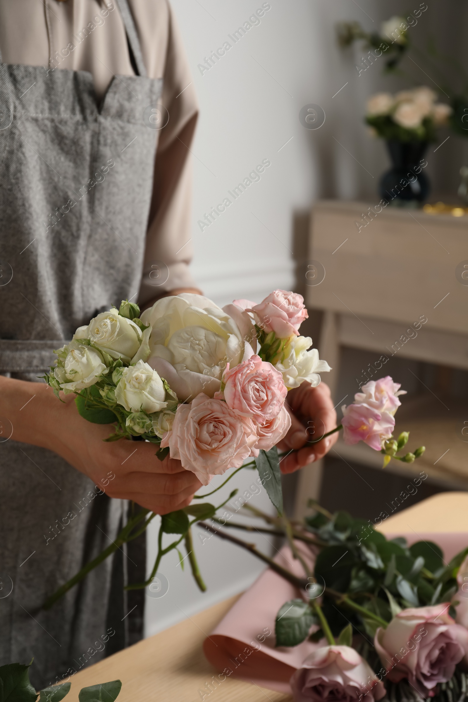 Photo of Florist creating beautiful bouquet at table indoors, closeup