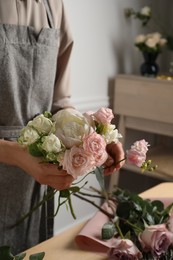 Florist creating beautiful bouquet at table indoors, closeup