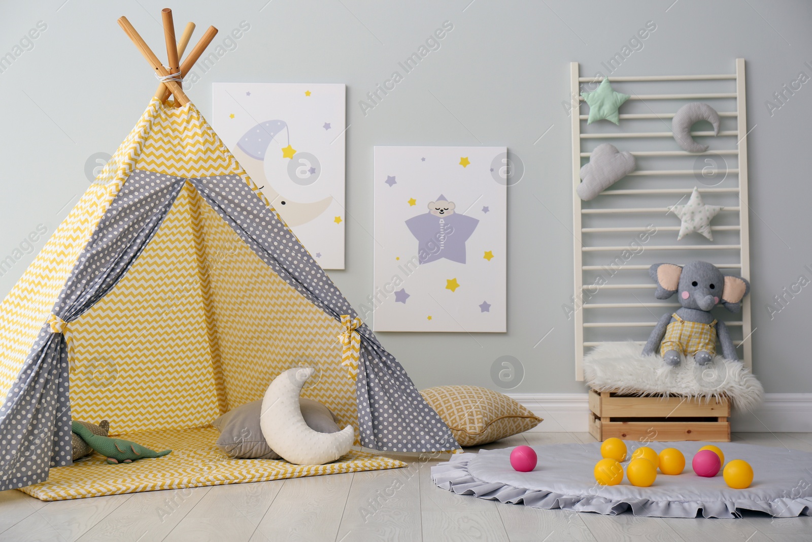 Photo of Stylish child's room interior with adorable paintings and play tent