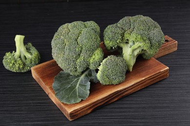 Board with fresh raw broccoli on black wooden table