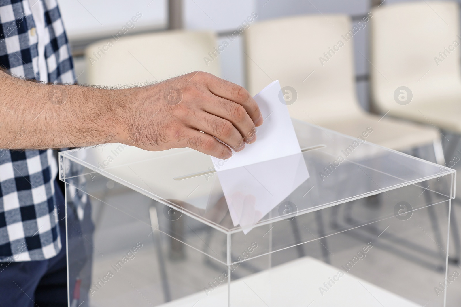 Photo of Man putting his vote into ballot box at polling station, closeup