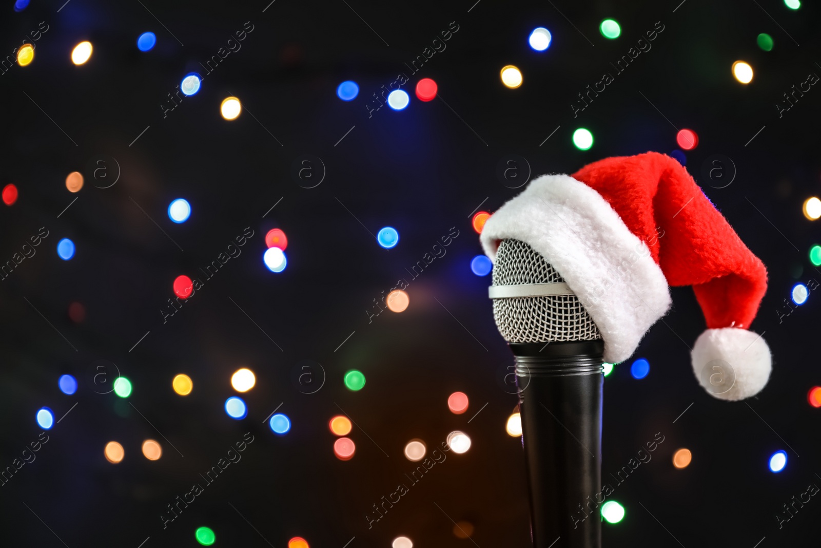 Photo of Microphone with Santa hat against blurred lights. Christmas music concept