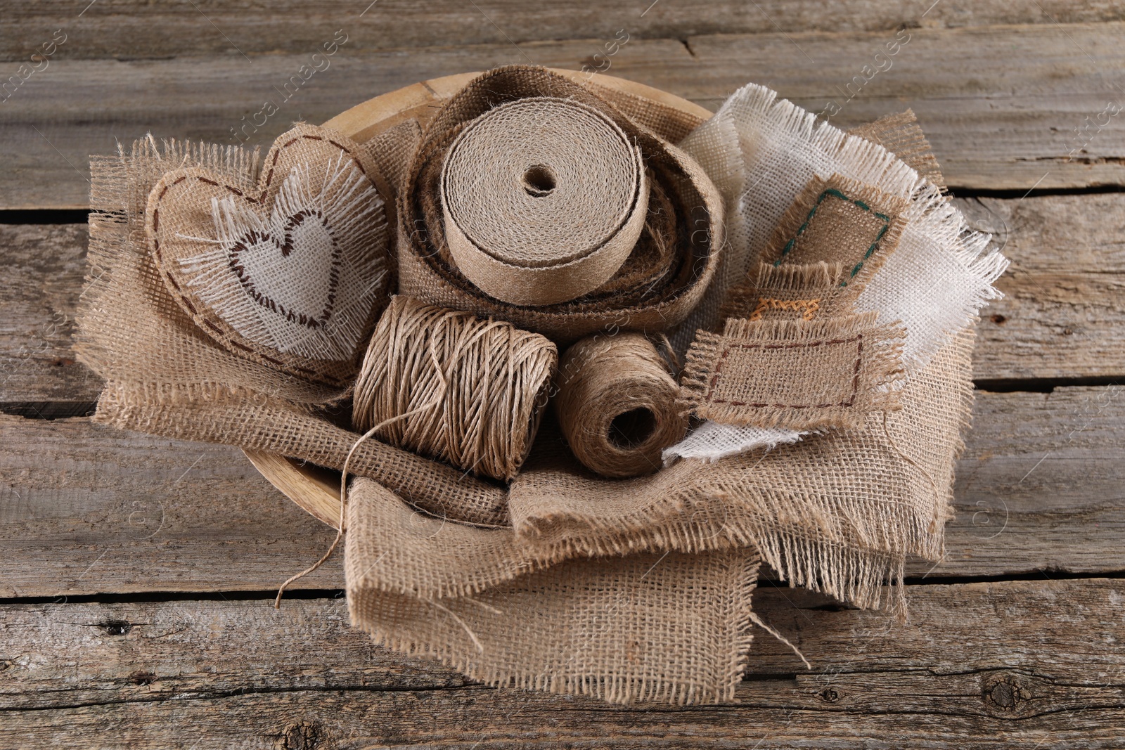 Photo of Pieces of burlap fabric and spools of twine on wooden table, above view