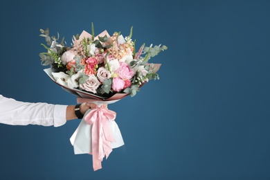 Photo of Man holding beautiful flower bouquet on blue background, closeup view. Space for text